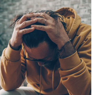 Man with head in hands trying to stop negative thoughts