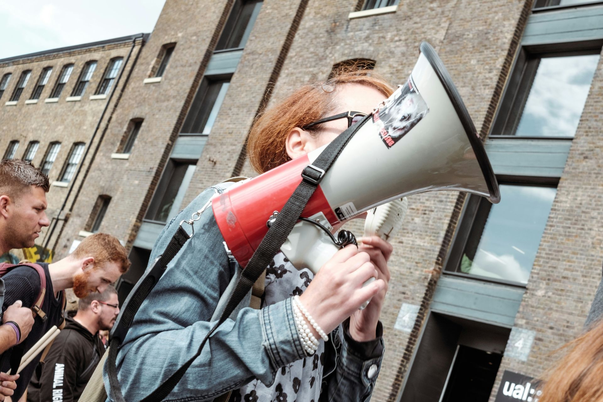 Person with red hair holding a megaphone walks in a crowd