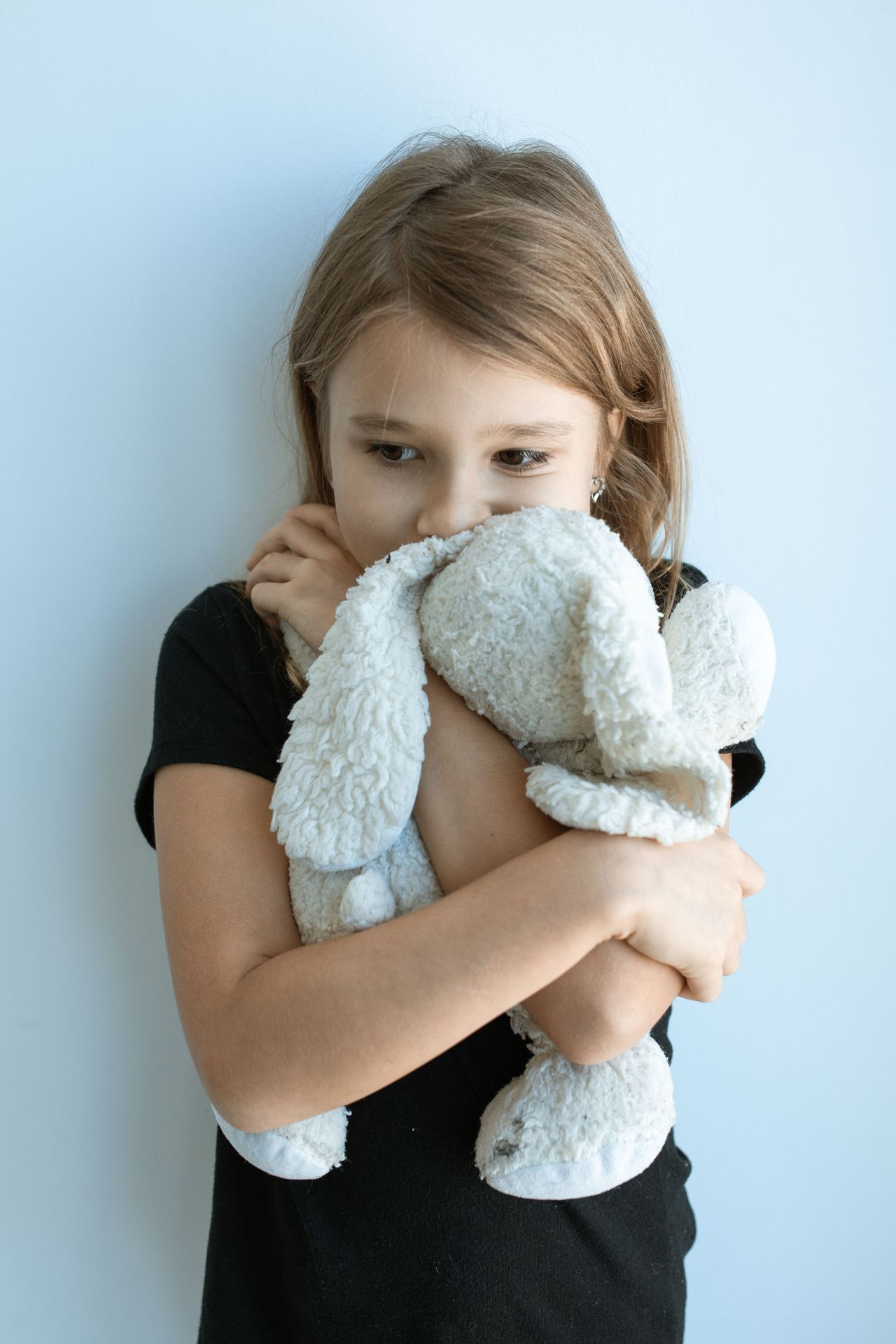 Young girl hugging a worn stuffed rabbit, illustrating childhood anxiety and parent therapy support in California.