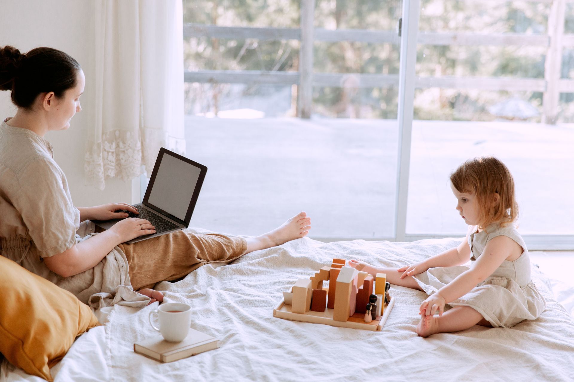 Mom attends online parenting therapy from home while her daughter plays nearby.