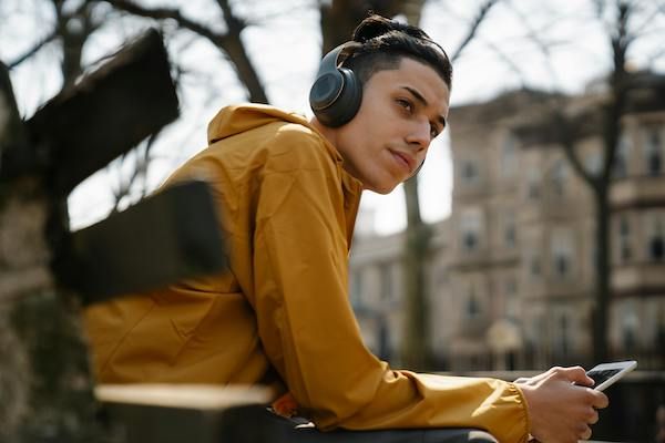 teenager sitting on bench listening to headphones