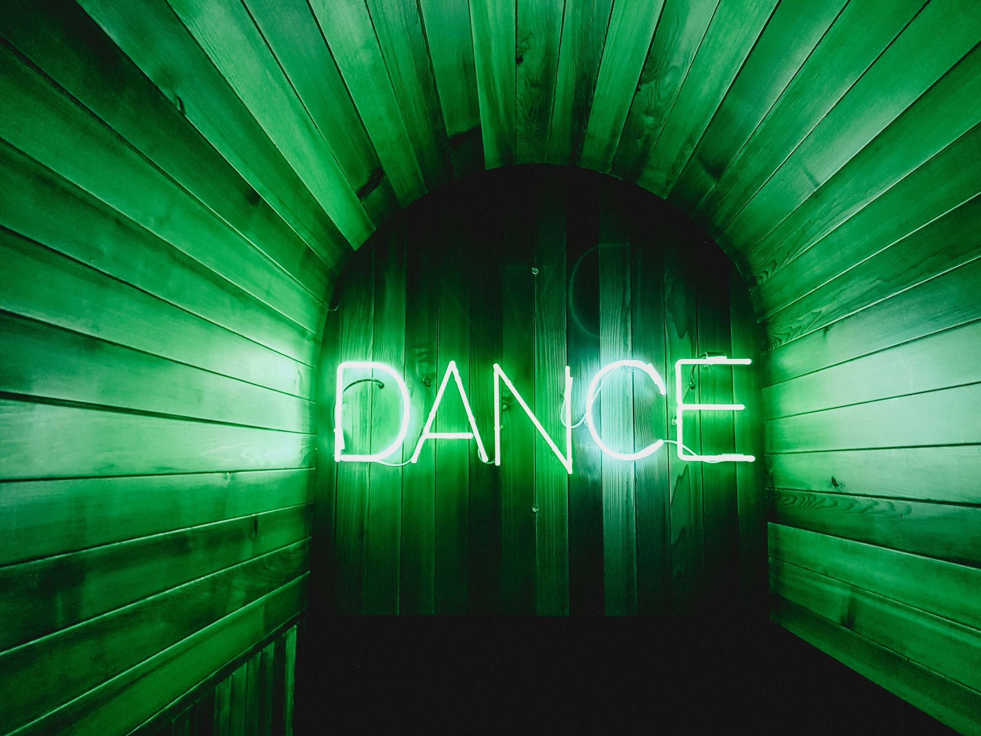 neon green light spelling out DANCE in a at the end of a wooden hall. Dance for anxiety; coping skills for anxiety