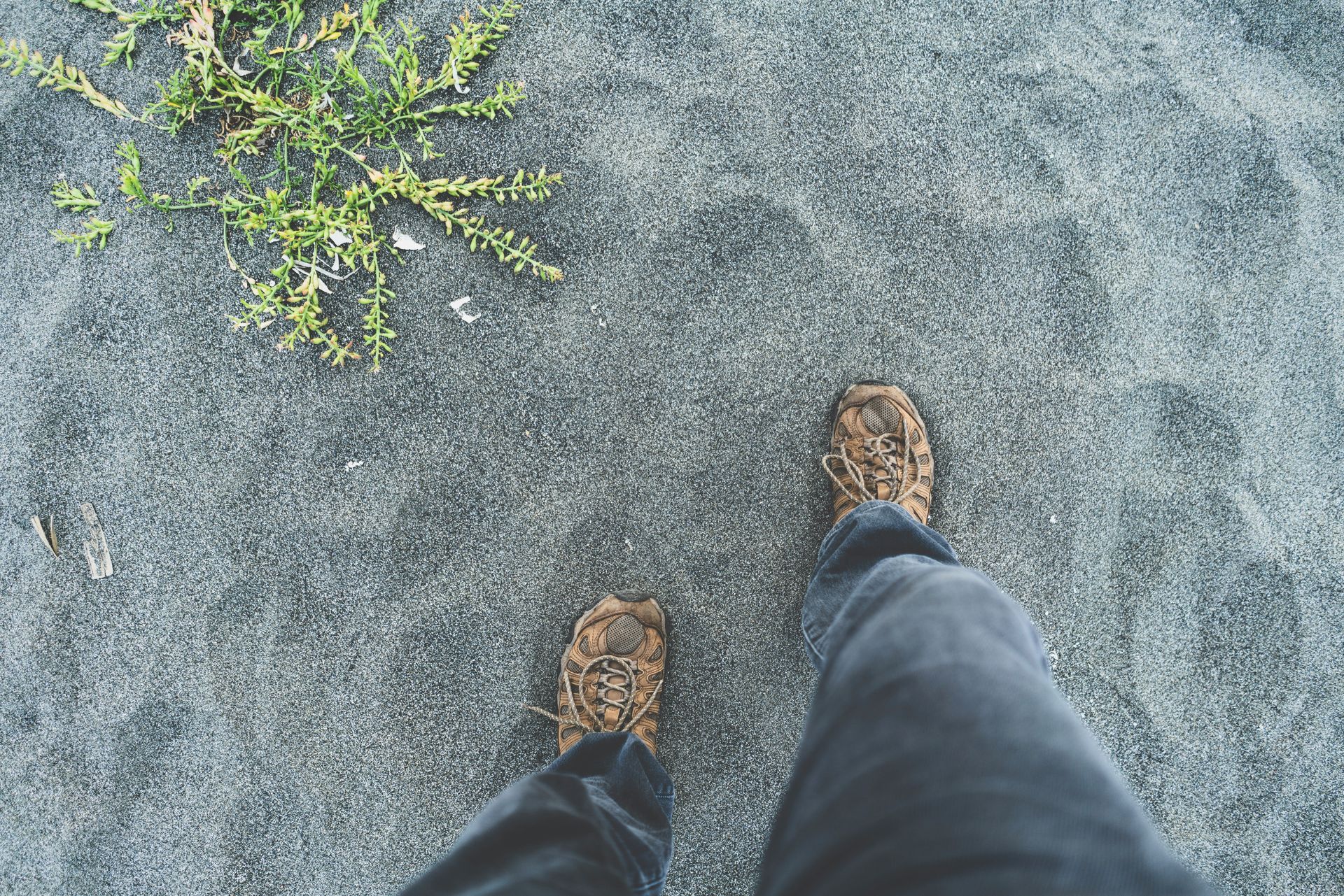 View looking down at the ground at hiking boots and gray sand. Habits that improve mental health