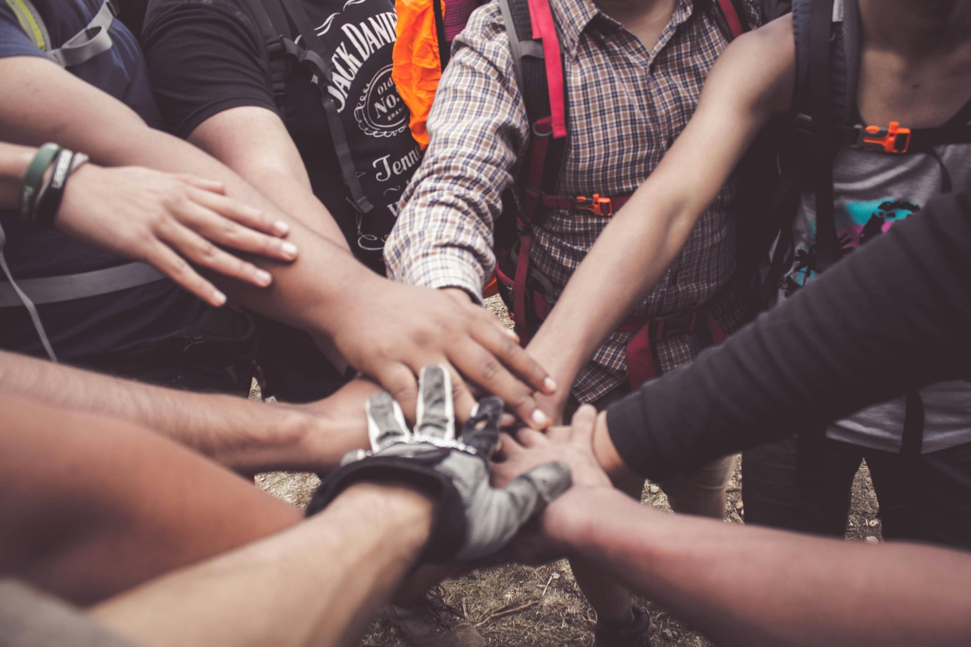 Group of people with their hands together in the center of a circle. May 2024: Mental Health Awareness Month