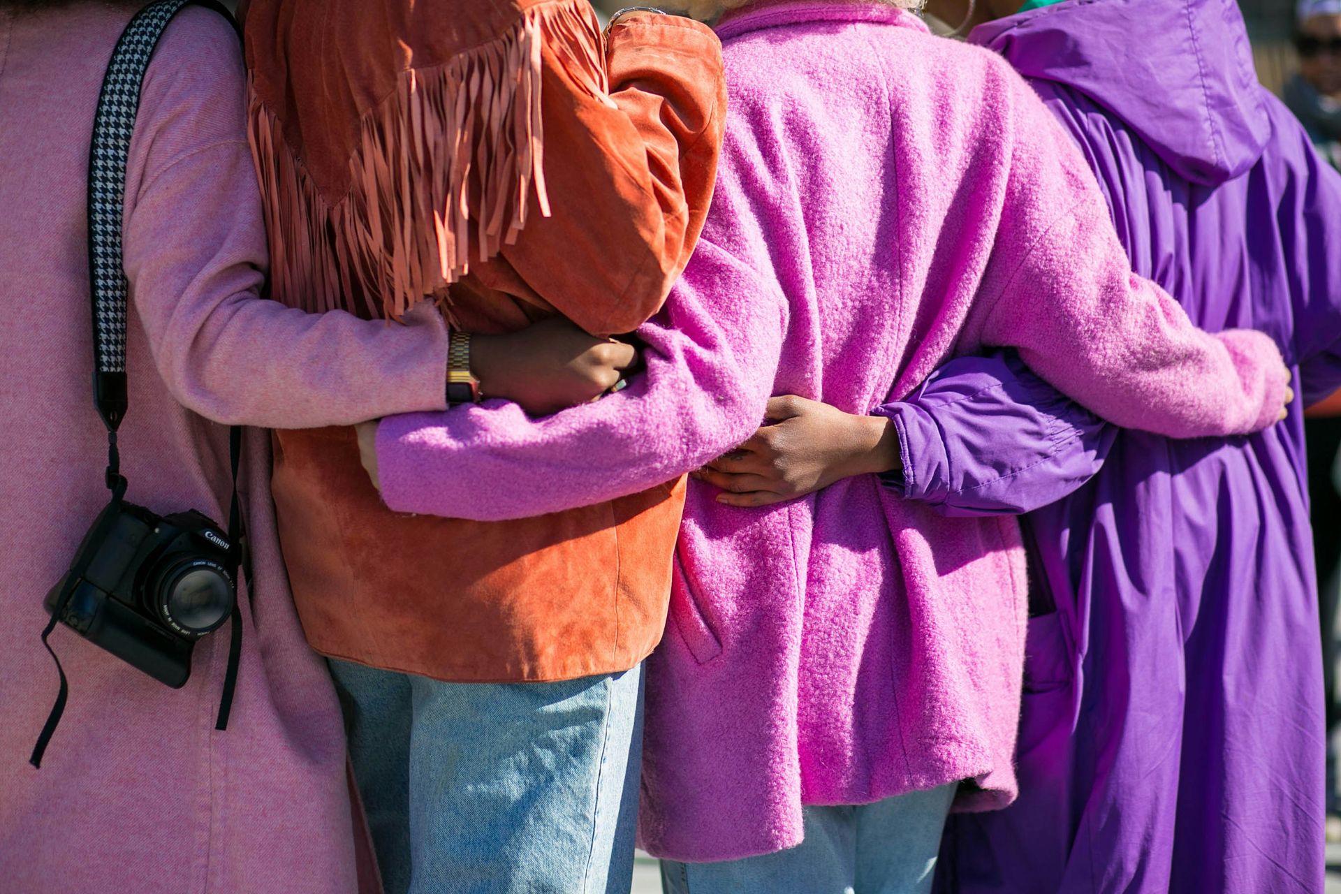 four people wearing pink purple and orange sweaters.