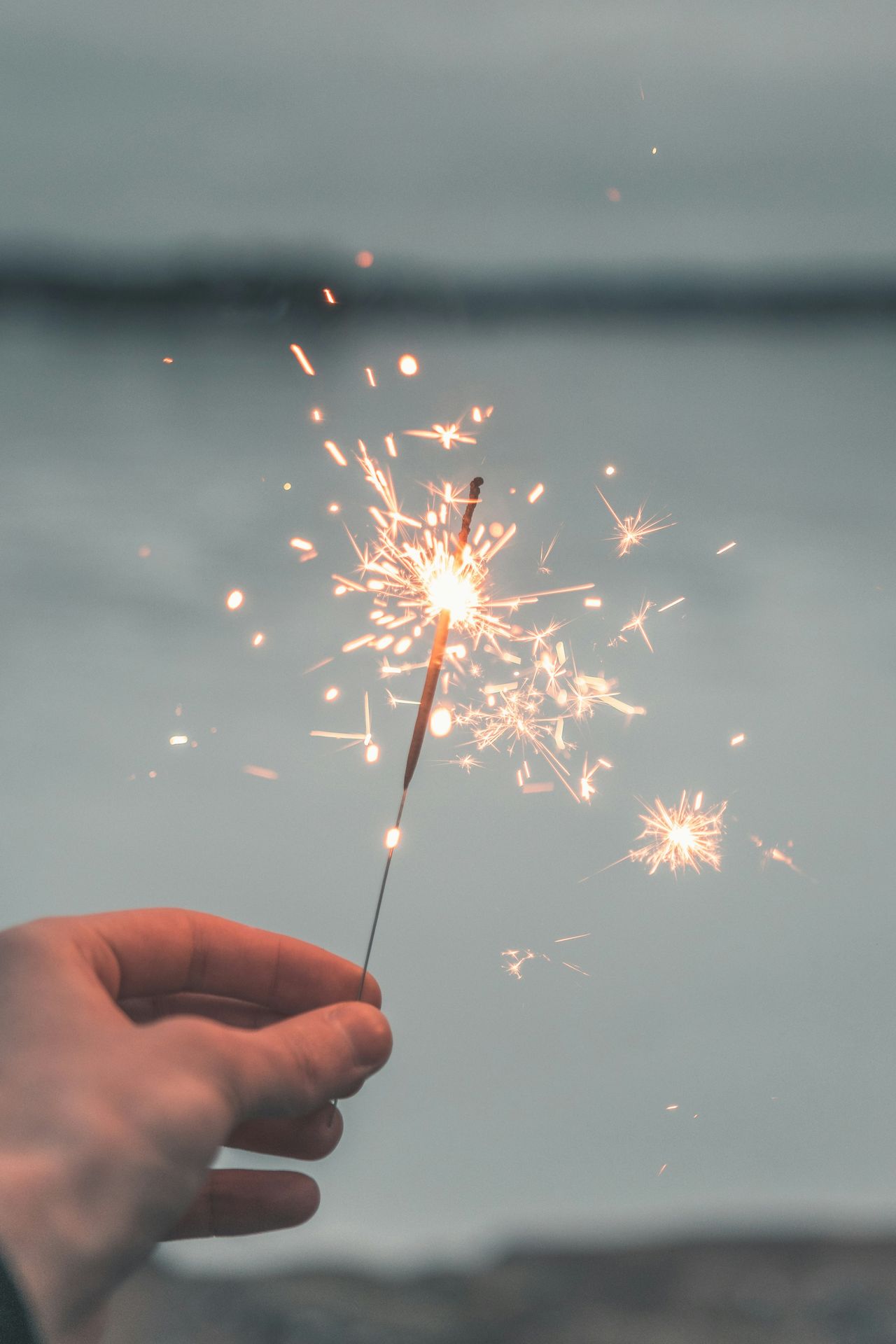 a white hand holding a sparkler