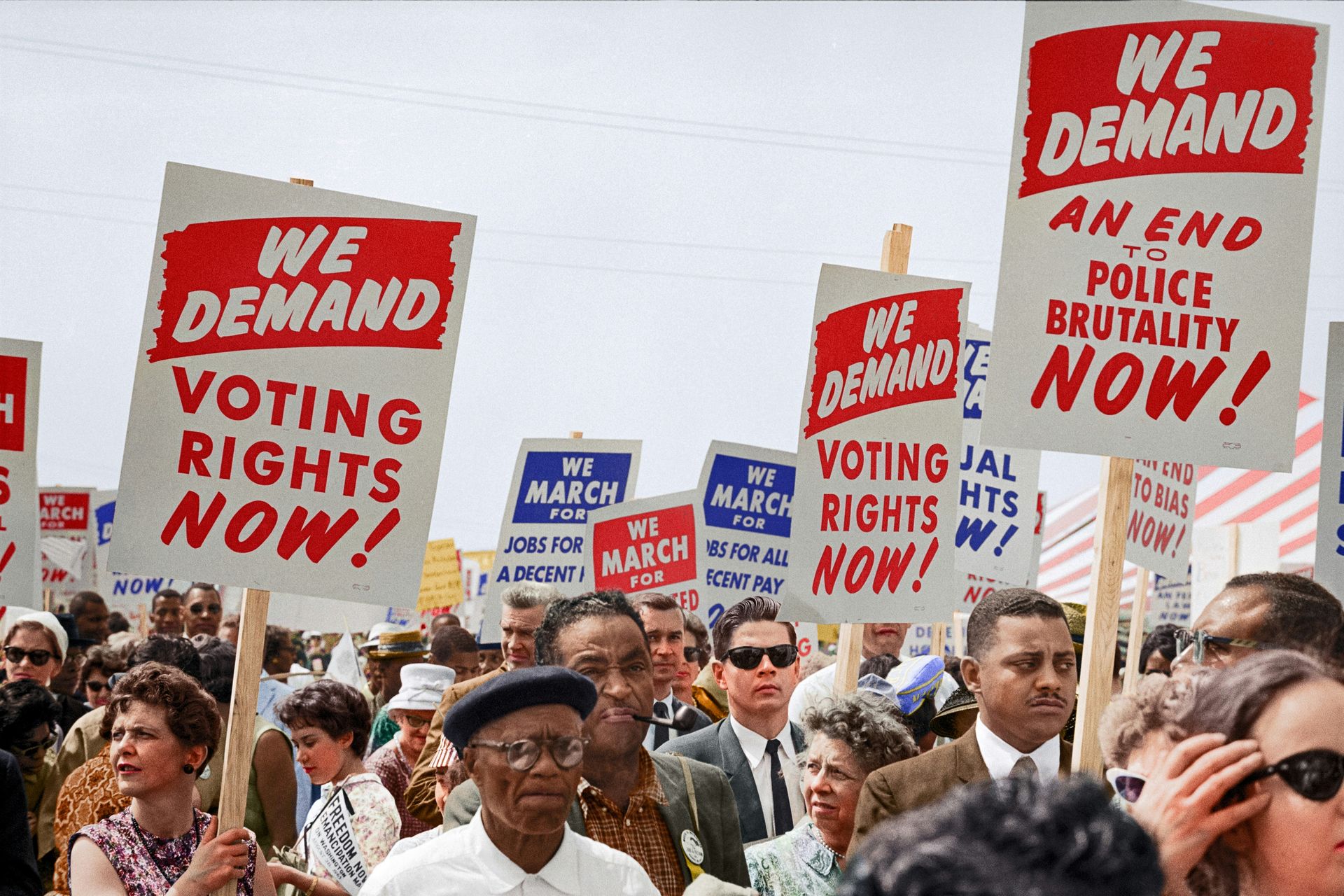 picture from civil rights protests of signs saying "we demand an end to police brutality" and "we demand voting rights now"