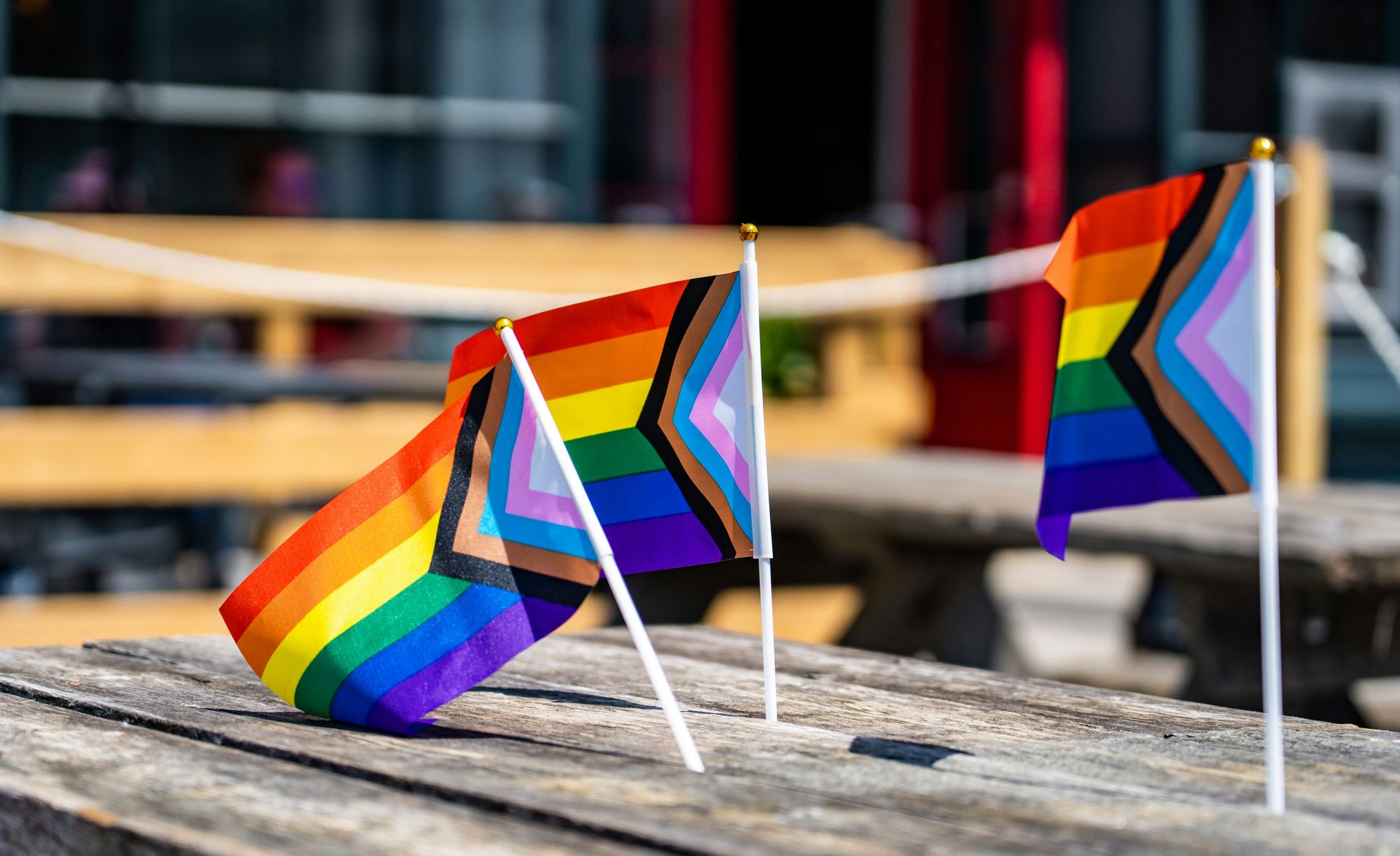 Trans and BIPOC Pride flags on a wooden table, LGBTQ+ perinatal and postpartum mood and anxiety disorders therapist alaska