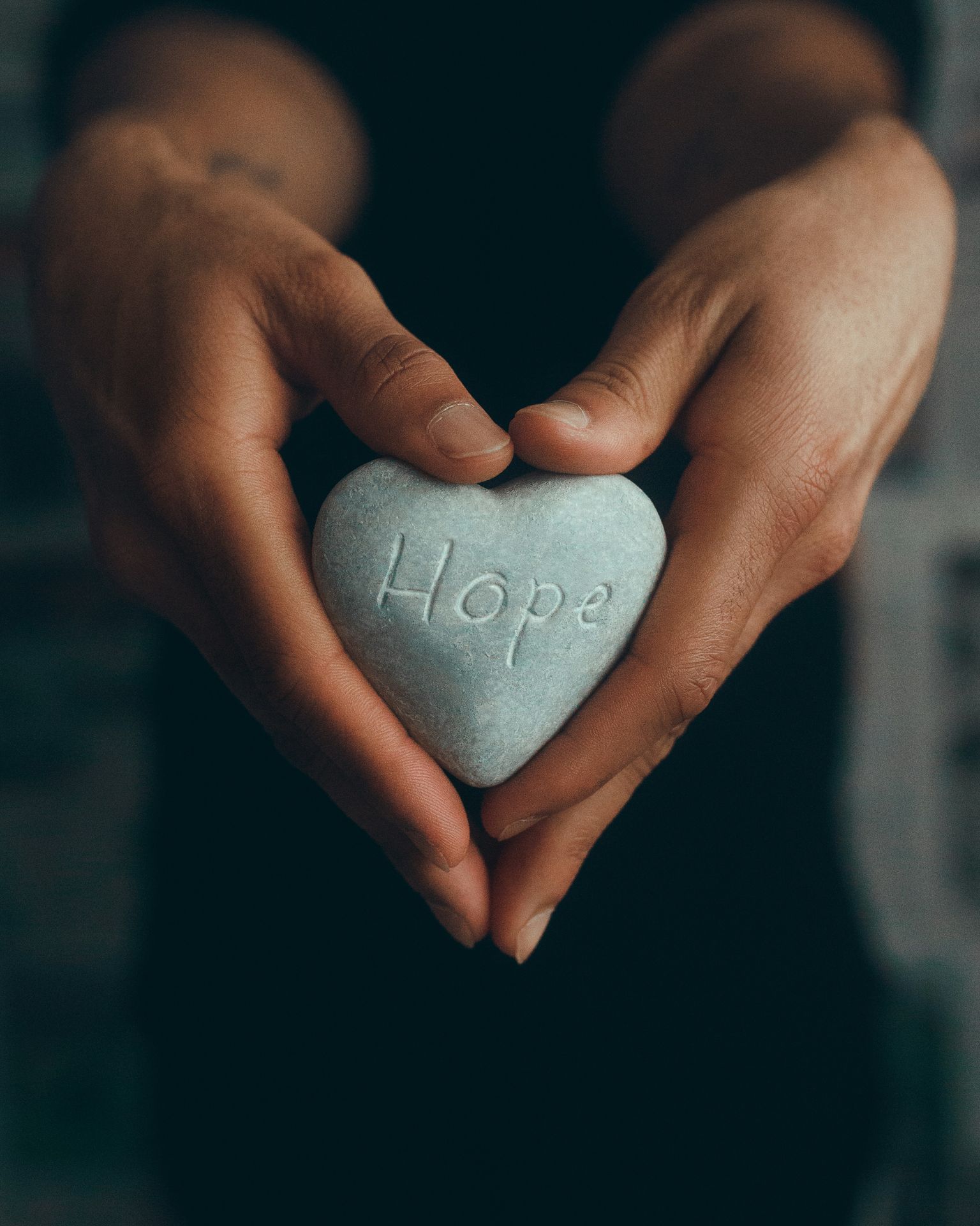 Hands holding a light gray heart shaped rock with the word HOPE etched on it. TBI resources Alaska, TBI Recovery