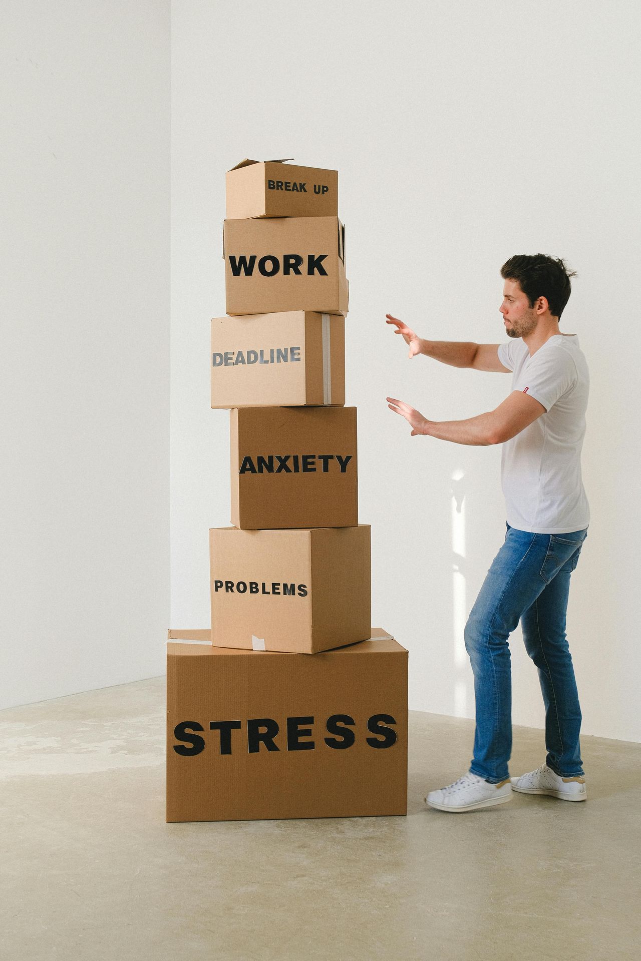 White man standing next to boxes labeled, "work," "break up," "deadline," "anxiety," "problems," "stress". anxiety therapy alaska online