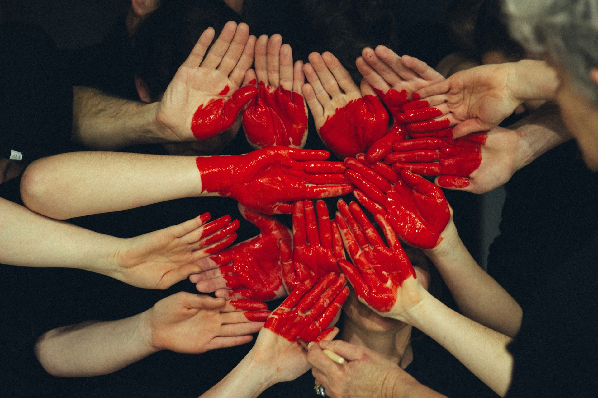 hands shaped together and red paint depicting a heart