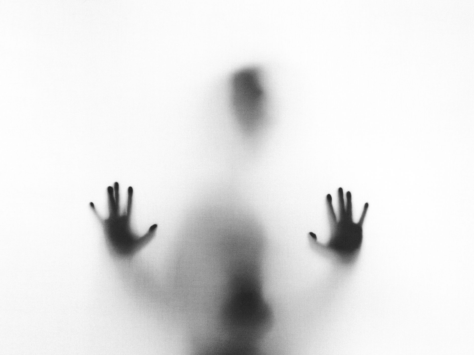 figure behind glass, obscured through white light and dark shadow