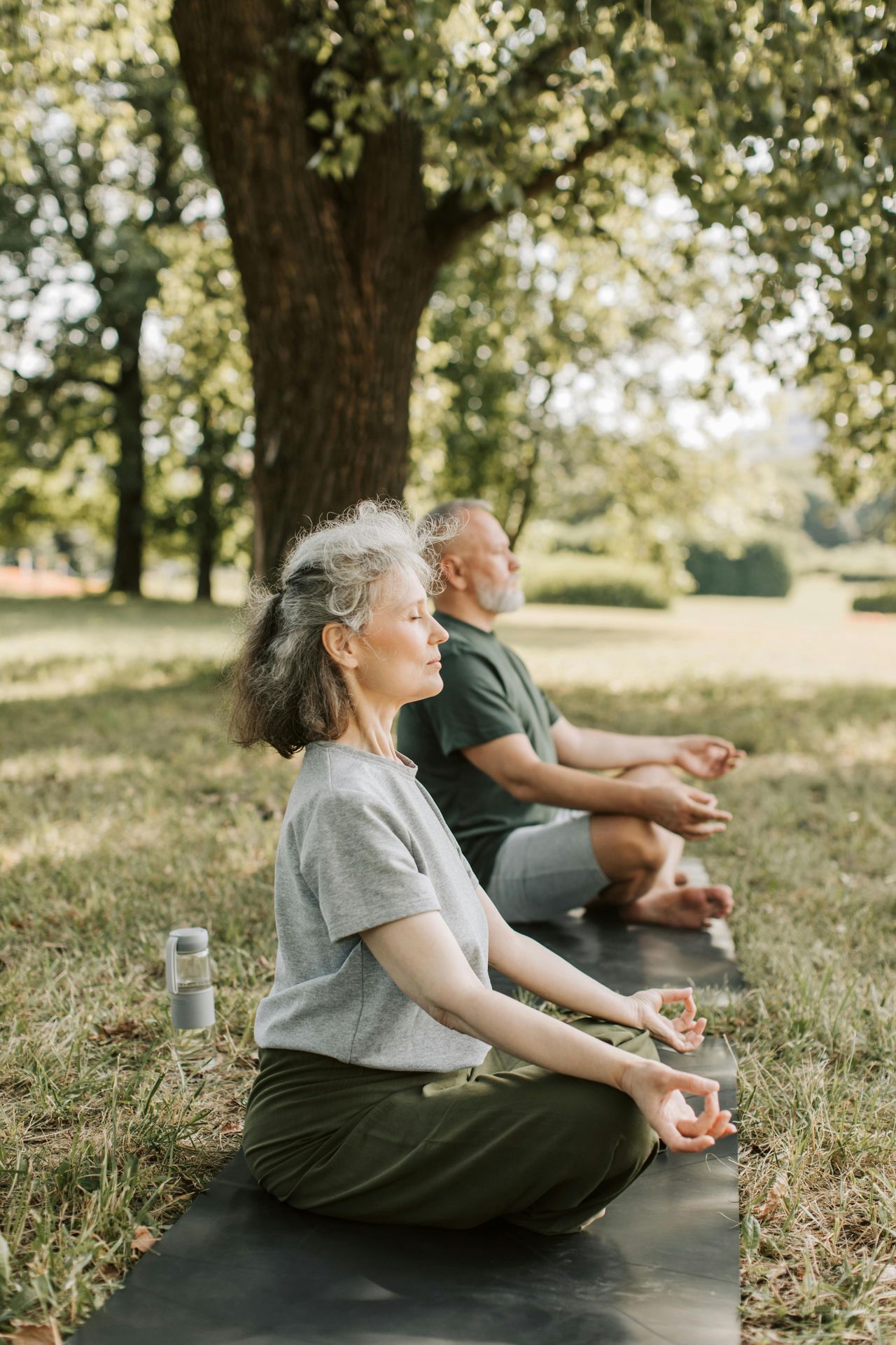 Senior white man and woman sitting cross legged outside focusing on their breath. coping skills for anxiety how to manage anxiety