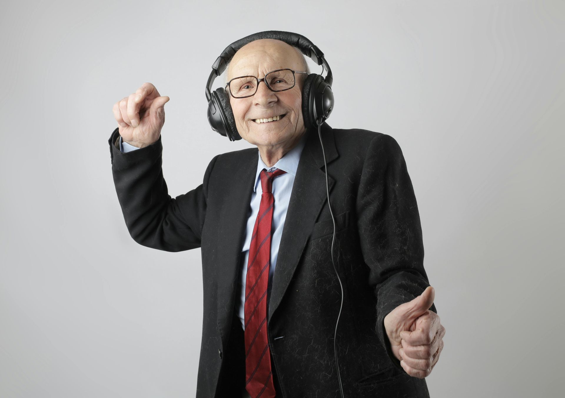 Senior white man in a suit listtening to music, looking happy. 45 regulation activities to boost well-being