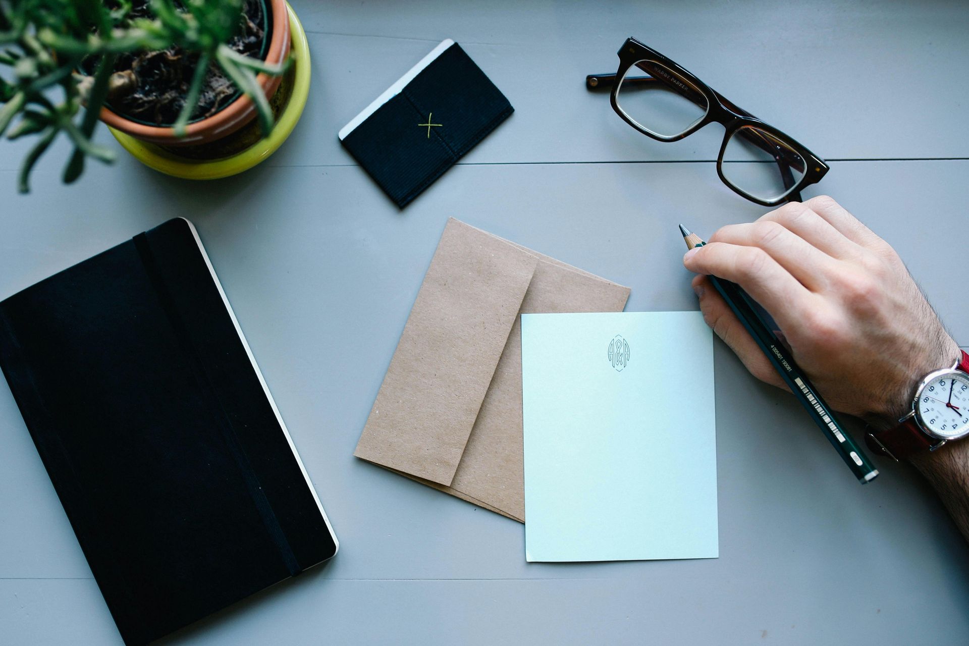 white hand holding a pen over stationary on a desk tips to manage holiday stress