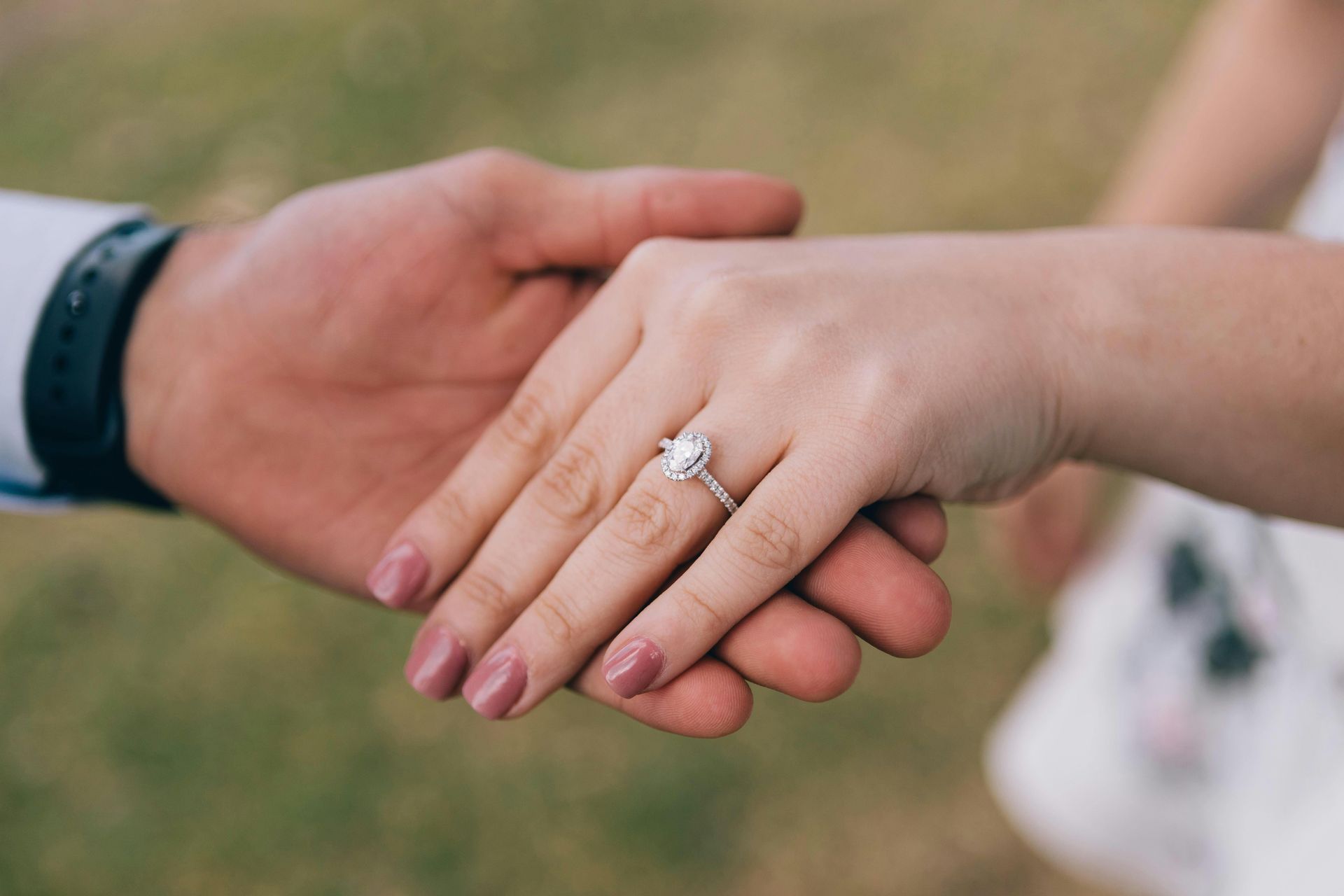 two people handing hands . woman is wearing engagement ring.