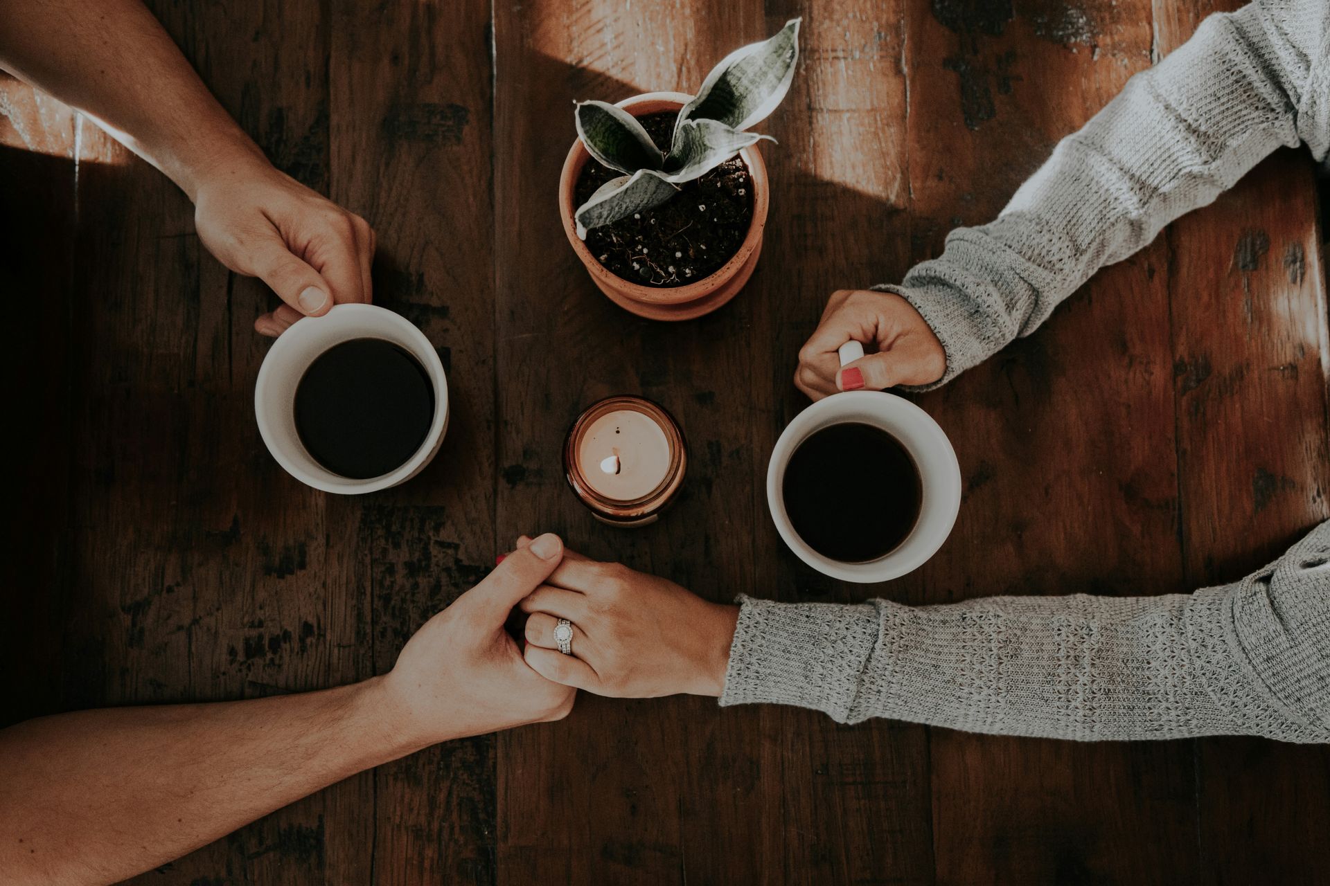 couple holding hands at table with coffee