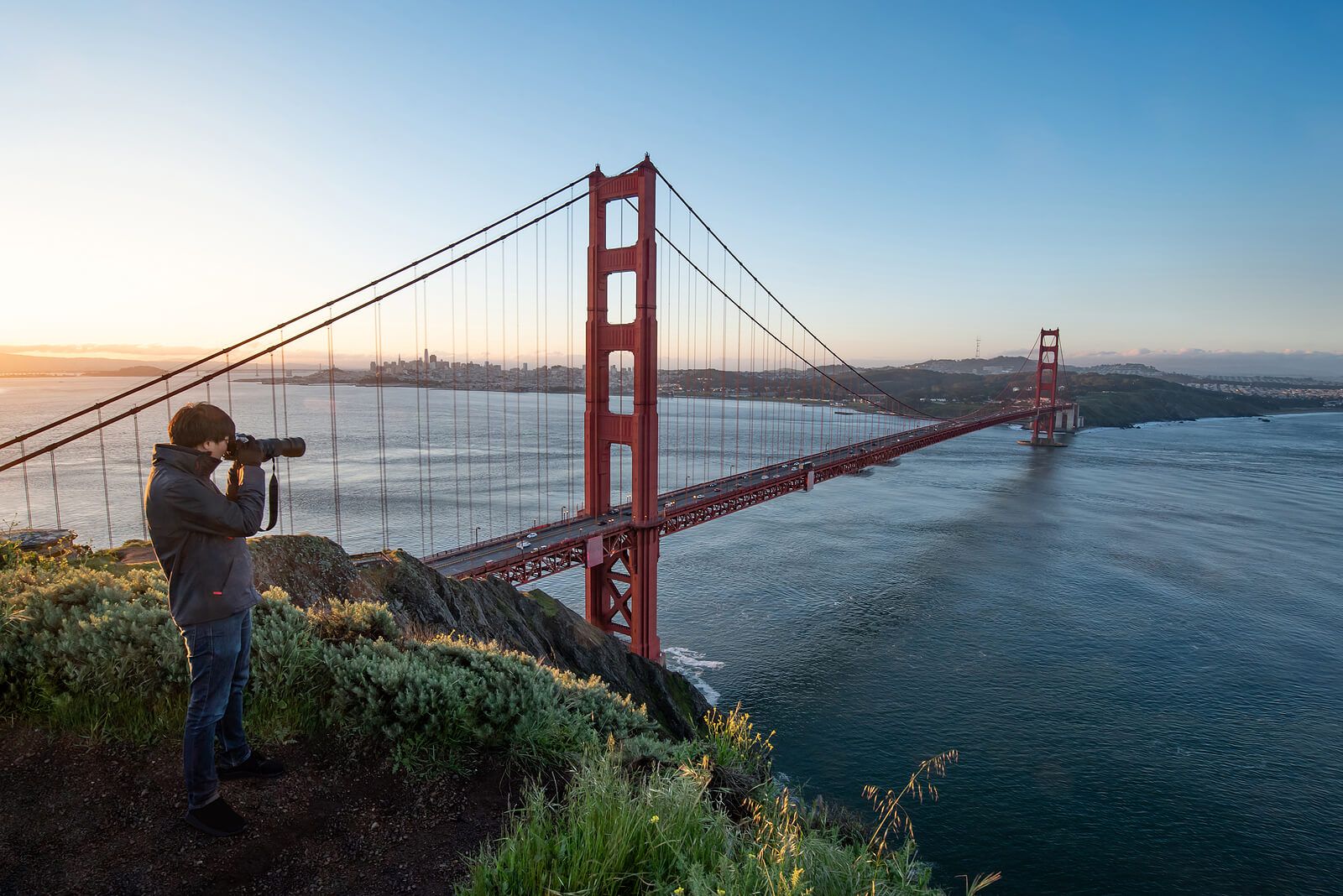 A man standing taking a photo of the San Francisco Bridge | grief therapist in san francisco, ca | grief therapy in san francisco, ca | grief counseling san francisco, ca | 94122 | 94539 | 94110 