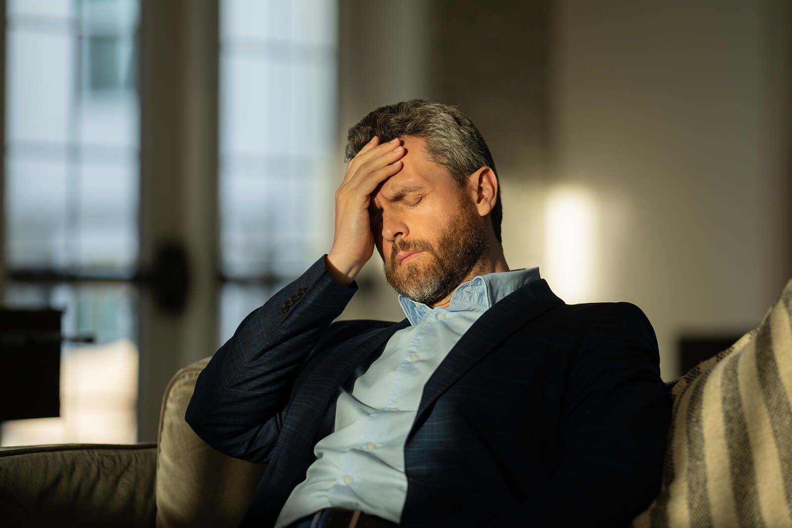 A man holding his forehead with his hand while closing his eyes | grief counselor san francisco | loss and grief treatment san francisco | therapist for grief san francisco | 94539 | 94110 | 94112