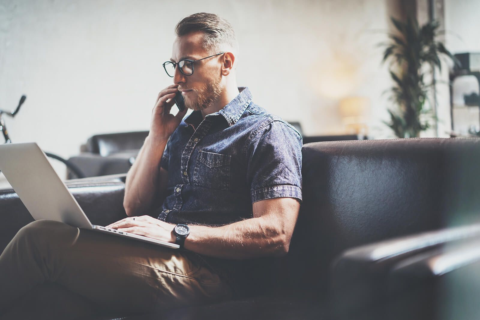 A man sitting on the couch working on a laptop & on the phone | grief counselor san francisco, ca | grief counseling san francisco | grief therapy in san francisco, ca | 94121 | 94607 | 94608