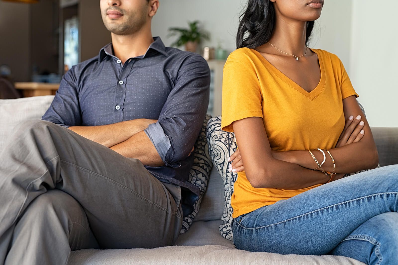 A couple crossing their arms while sitting away from each other on a couch | grief therapist in san francisco, ca | grief therapy in san francisco, ca | grief counseling san francisco, ca | 94110 | 94112 | 94116