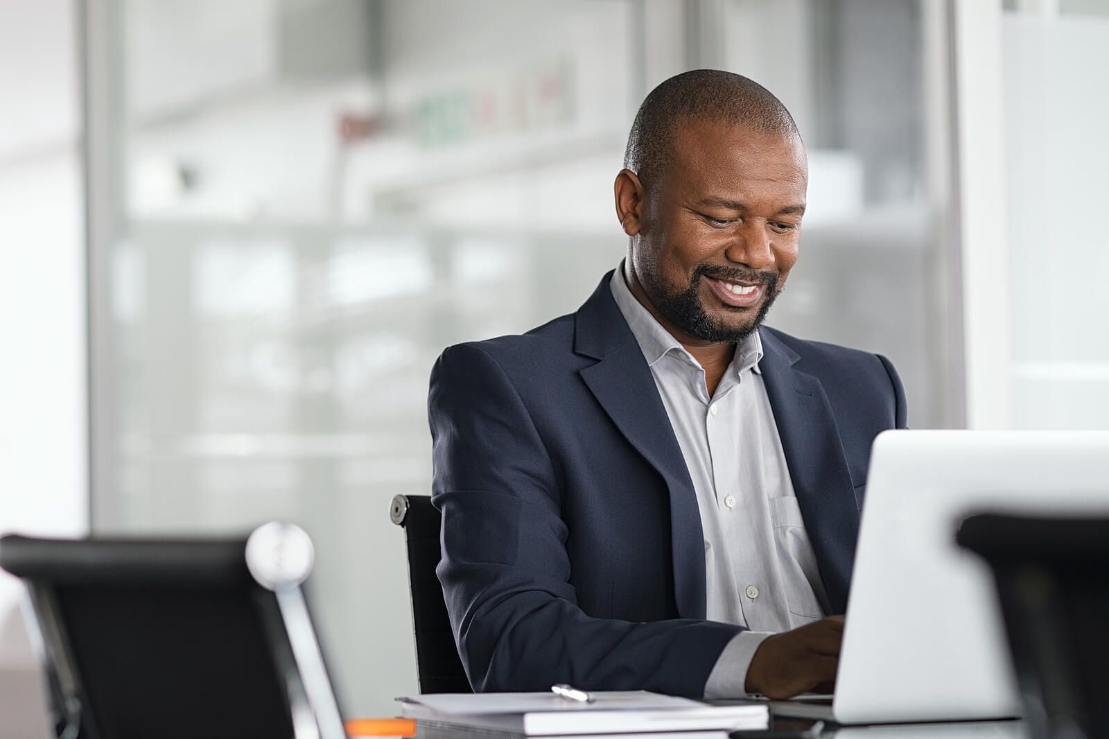 A happy black man typing on his computer while smiling | counseling for men san francisco | men's therapist san francisco, ca | men's therapy san francisco, ca | 94607 | 94608 | 94609