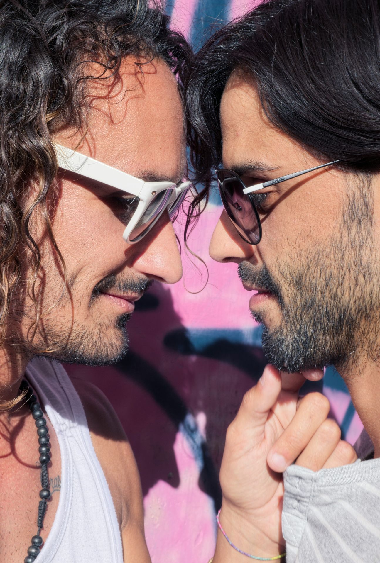 close up of a male gay couple staring into each others' eyes one is touching the other's chin and they both have stubbly beards