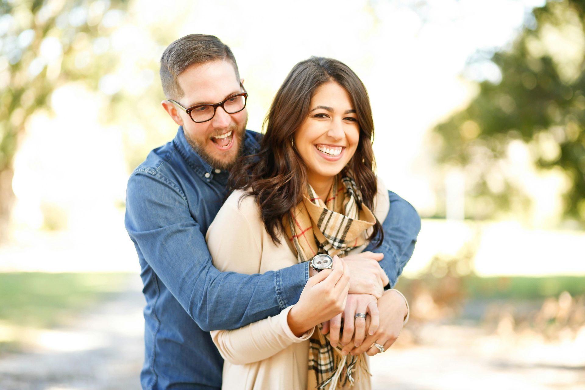 cis-gendered couple the woman being hugged from behind both smiling