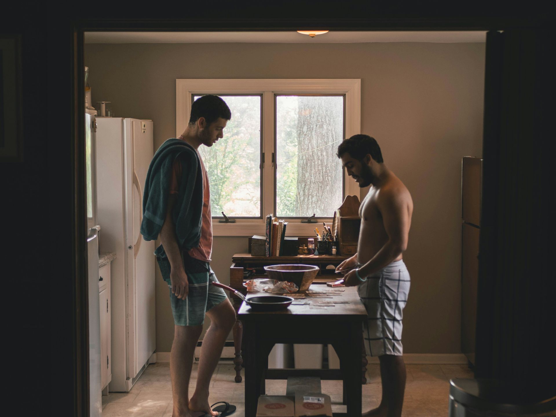 gay couple in their kitchen standing opposite each other with a table in between