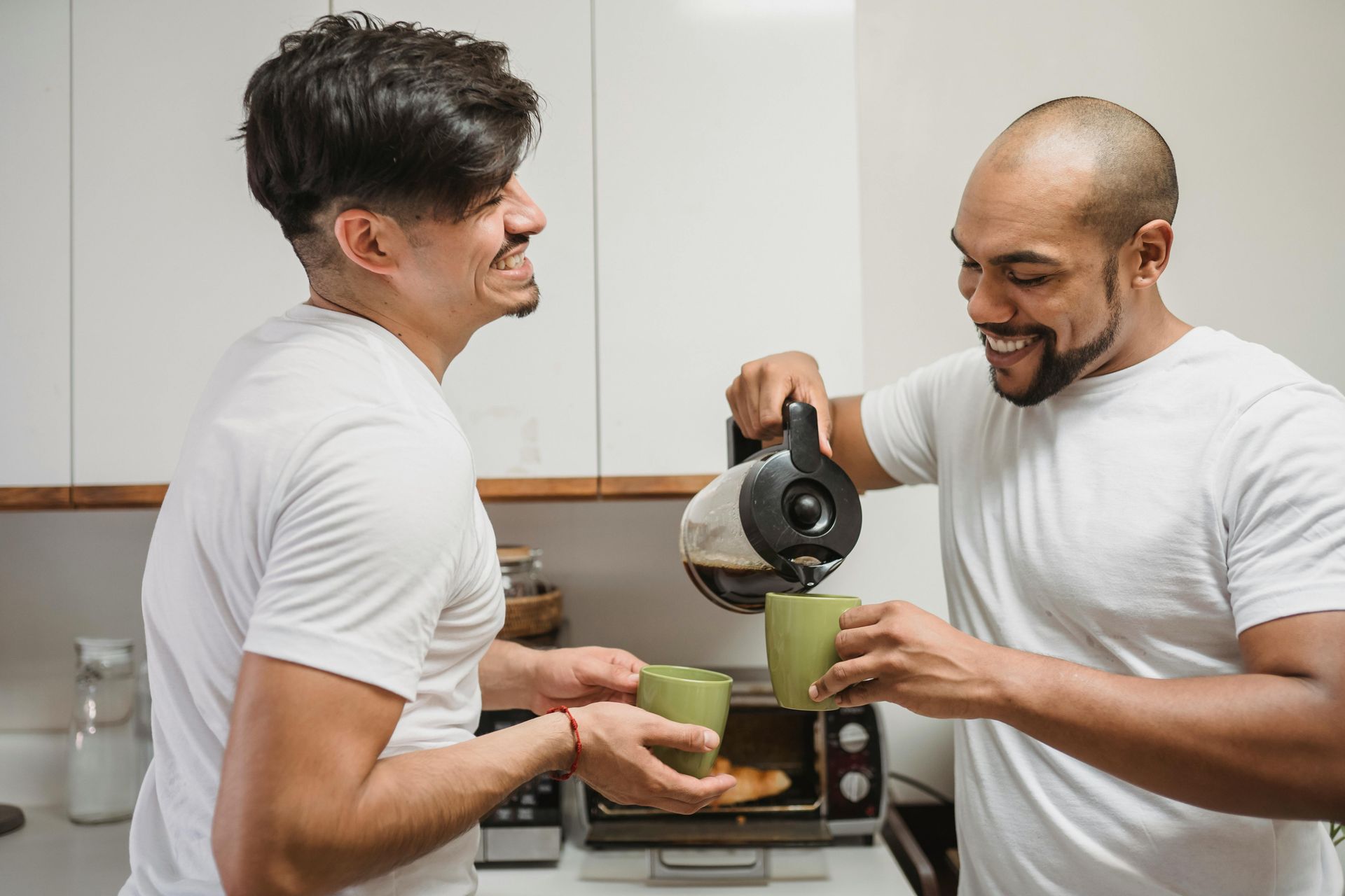 gay couple in a kitchen smiling with coffee cups