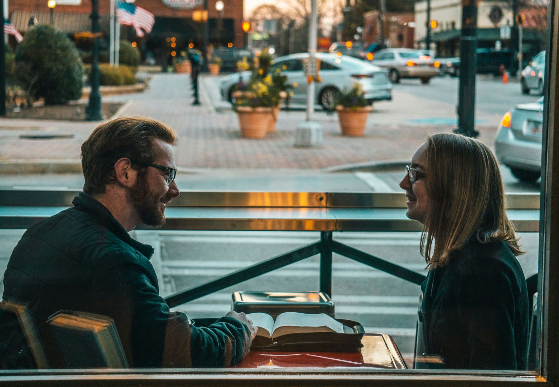 couple sitting in a coffee shop window smiling at each other