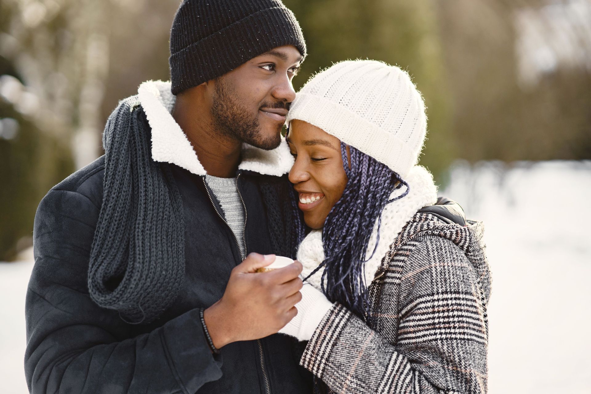 couple outside in the snow wearing snow caps and holding hands and smiling together