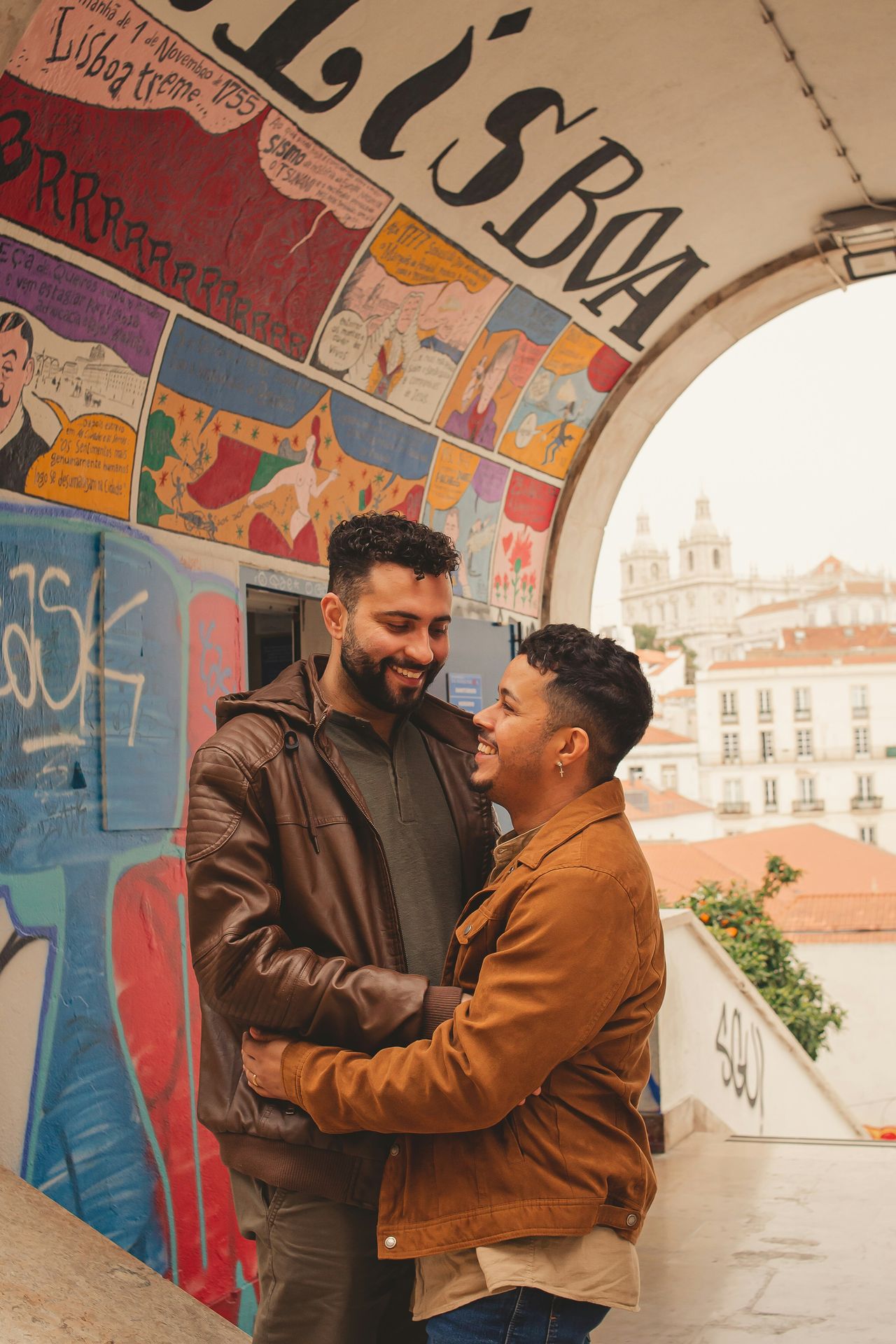 gay couple smiling and hugging under a painted arch