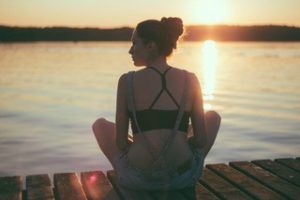 A woman sitting on a dock at the lake incorporating mindfulness techniques she learned during therapy in Katy, TX 77494