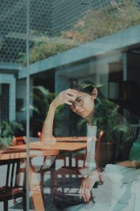 A woman sitting at a table alone having difficulty overcoming her negative thoughts before her CBT session in Katy, TX 77494