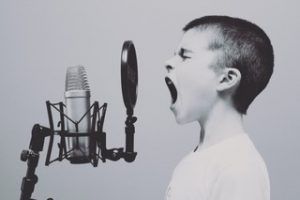 A small boy yelling into a microphone about what he needs in regards to nutritional health. Tips learned about healthy bodyweight maintenance in a body image group in Katy, TX 77494