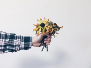 Man holding dead flowers after feeling unappreciated in his toxic work environment