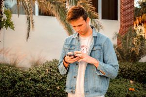 Young man texting on his phone outside at school, Helping Middle School Kids Adjust blog, counseling center at cinco ranch, katy texas, fulshear, richmond texas, 77494