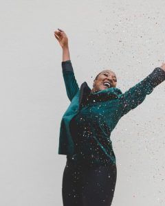 A woman smiling and holding her hands up celebrating her success. Represents the need for counseling to discuss feeling stuck in life in Katy, TX 77494