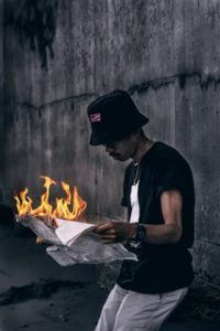 A man holding a newspaper on fire depicting how someone may feel from work burnout