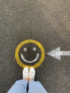 A teenager standing by a smiley face chalk art that she drew after her CBT session to overcome negative thinking