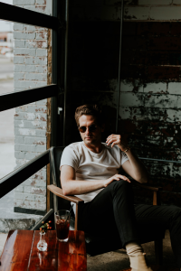 A man sitting in a chair waiting for his men's therapy session in Katy, TX to begin. He is learning about healthy masculinity. 