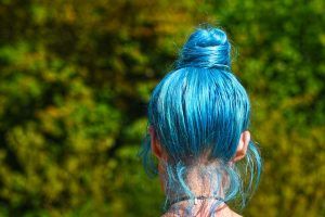 A teen girl with blue hair walking outside. Represents the need for parenting teens in Katy, TX 77494. Represents the need for therapy for teens and family therapy in Katy, TX 77494