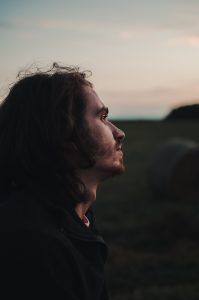 A man standing in a field thinking about his positive self-esteem after attending therapy in Katy, TX 77459