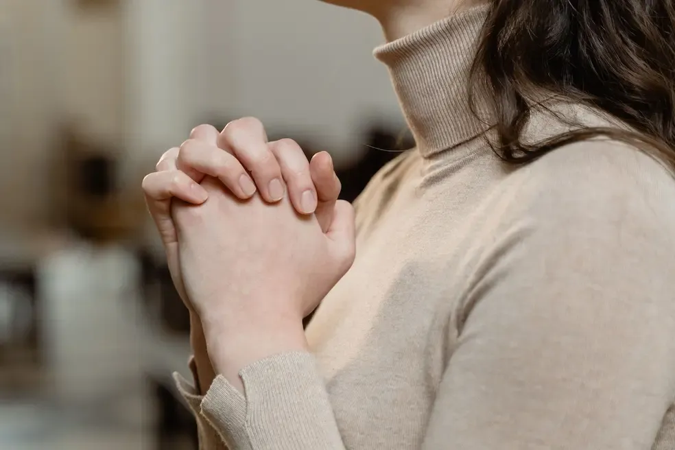 A woman with her hands in prayer.