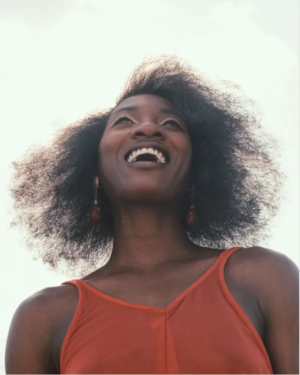A woman smiling wearing a red tanktop.