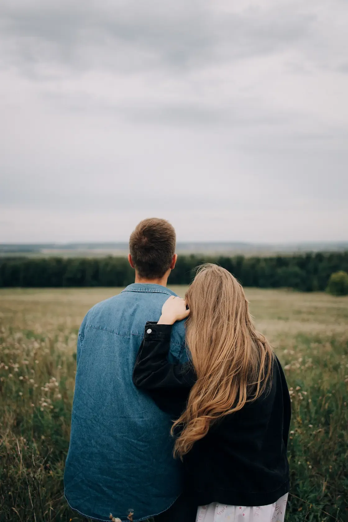 Back view of a couple standing in field.