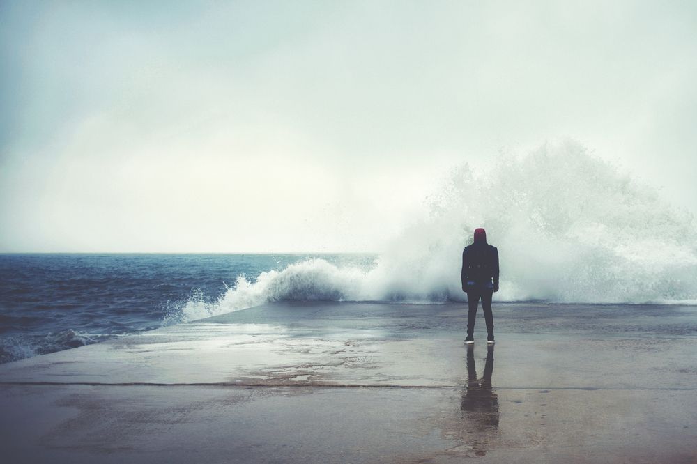 A person stands on a wet pier as waves crash, symbolizing overwhelm before healing. They’re exploring trauma treatment in palm beach county, fl and considering emdr therapy in palm beach county, fl. Many clients choose emdr intensives in palm beach county, fl to make faster progress.