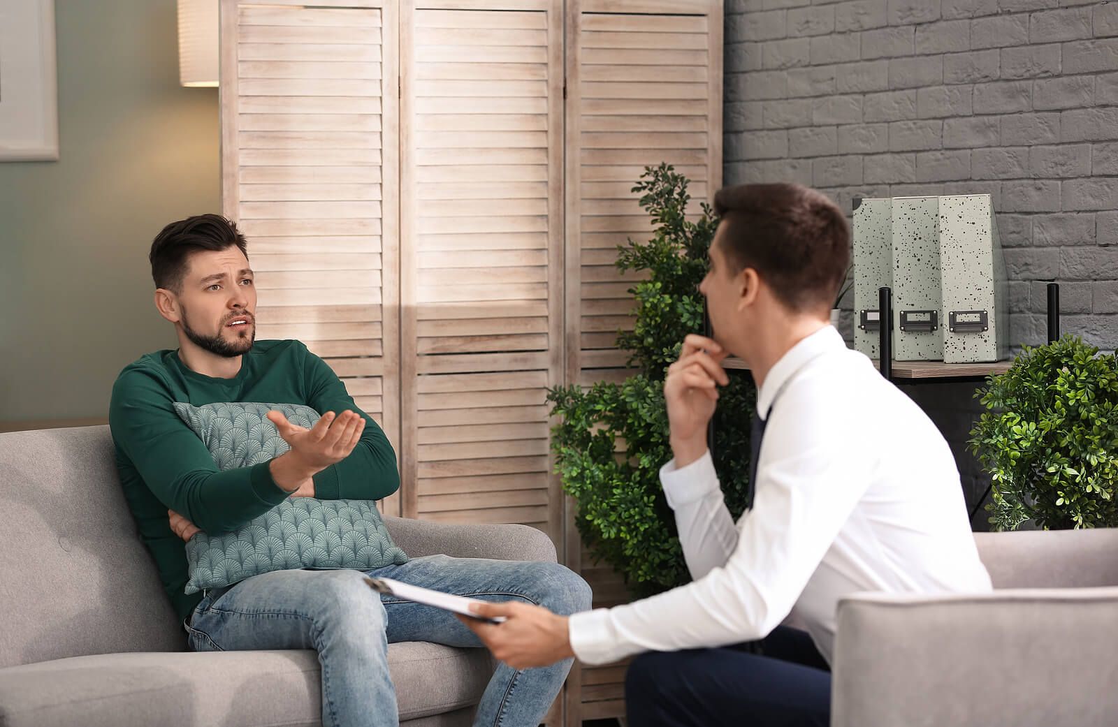 A man gestures while talking to his therapist, holding a pillow close as he works through difficult feelings, the kind of session an emdr therapist in Palm Beach County, FL might lead. An emdr intensive Delray Beach, FL or trauma treatment in Palm Beach County, FL can offer deeper support.