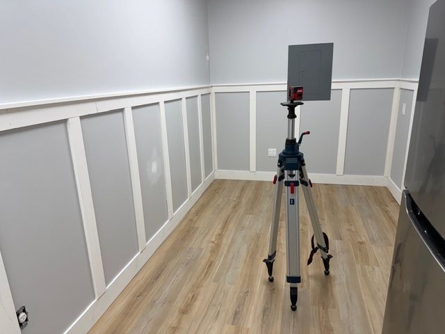 A freshly built board and batten breakroom mid-construction, with crisp white trim panels installed along the lower half of the walls and a laser level set up in the center of the room to ensure precise alignment. Even the behind-the-scenes spaces at this Delray Beach mental health therapist practice were built with care and attention to detail. Every room in the new Mangrove Therapy Group office was designed to reflect the same standard of quality that clients experience in their sessions.